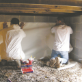 Right - Technicians use adhesive when installing the vapor barrier along the walls of this crawlspace. 