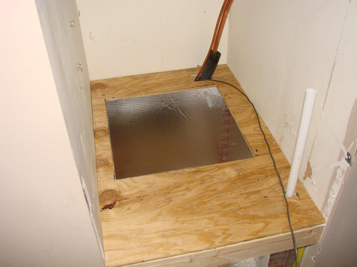 The plywood platform is installed on the support framing in the air handler closet. The plywood is carefully fitted around various piping.