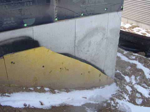 Exterior fiberglass insulation on this new home was (incorrectly) cut to terminate below-grade after backfill, which will expose the above-grade portions of the foundation wall to cold temperatures.