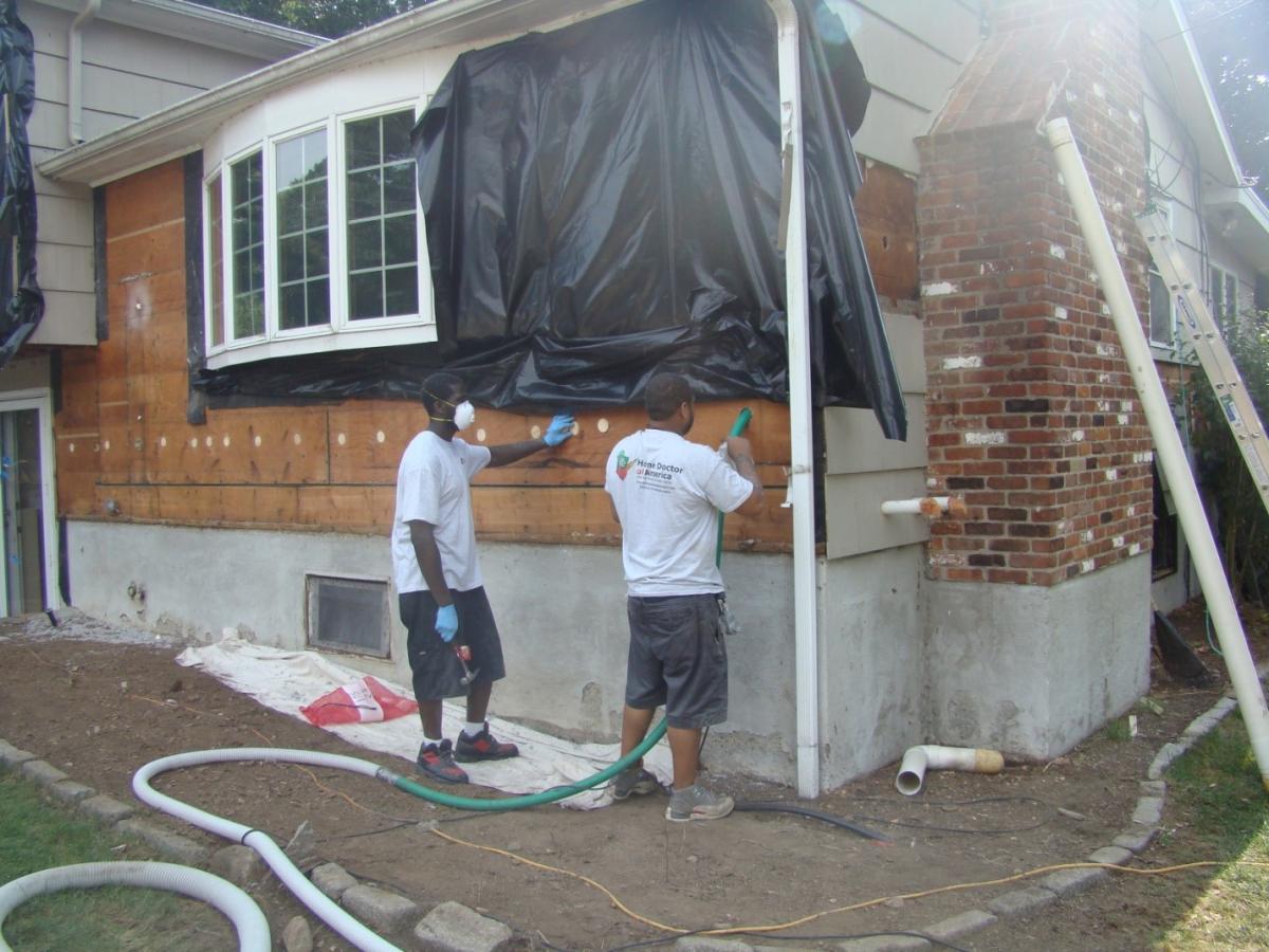 The siding has been removed so cellulose insulation can be dense-packed into the exterior walls of this home.