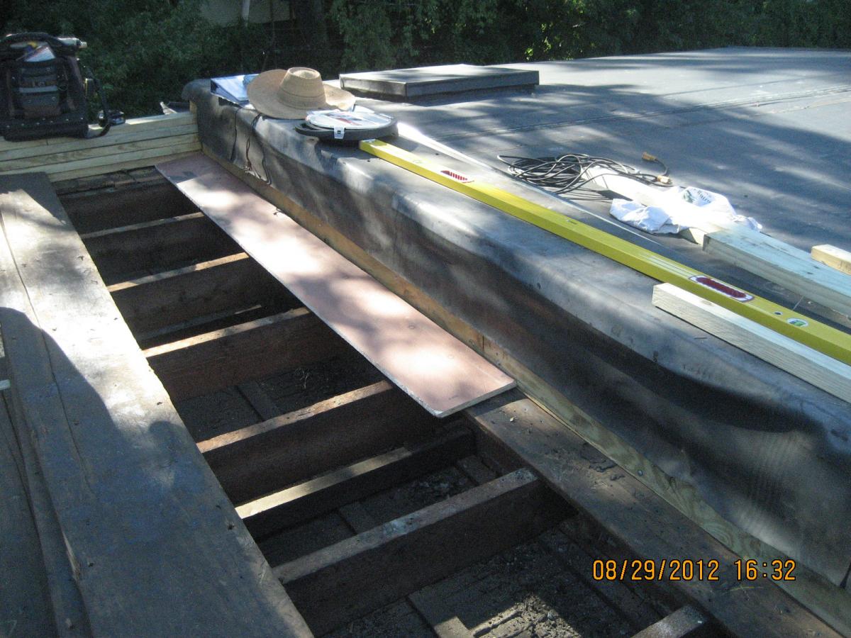 A strip of OSB sheathing is installed along the perimeter when retrofitting a flat roof with a parapet.