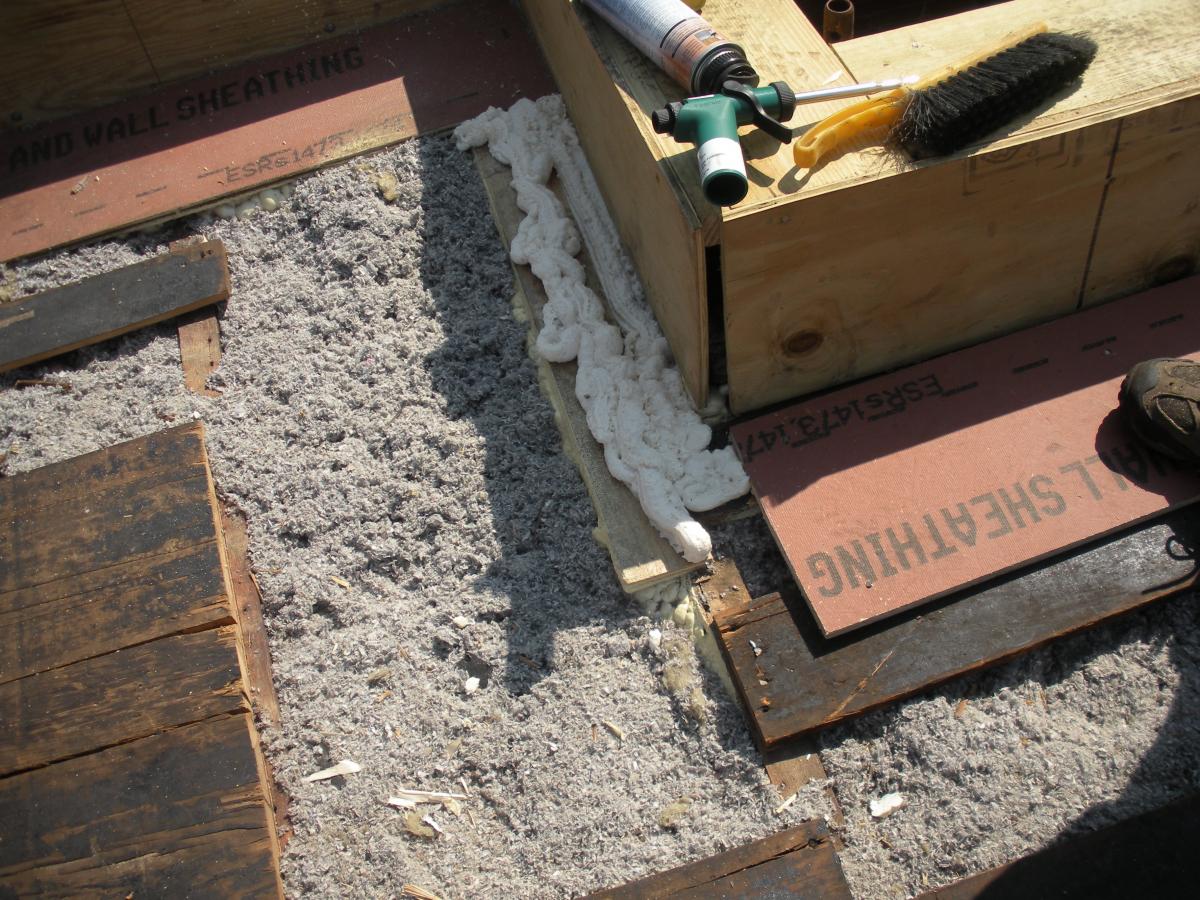 The base of the plywood parapet is air sealed with spray foam and fibrous insulation is installed in the rafter cavities in this flat roof retrofit.