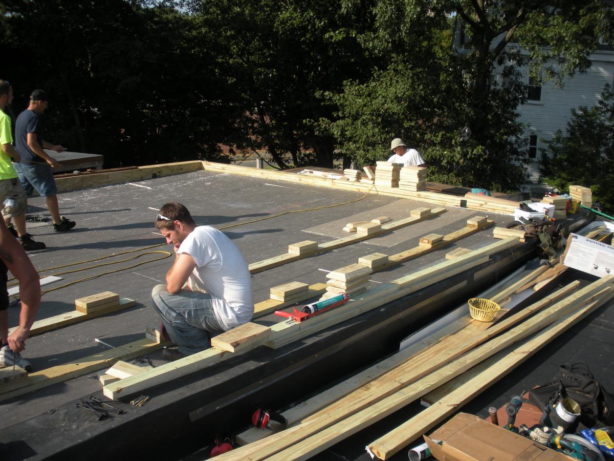 Wood blocking for future PV panel installation is installed in the layers of polyisocyanurate rigid foam insulation during a flat roof retrofit.