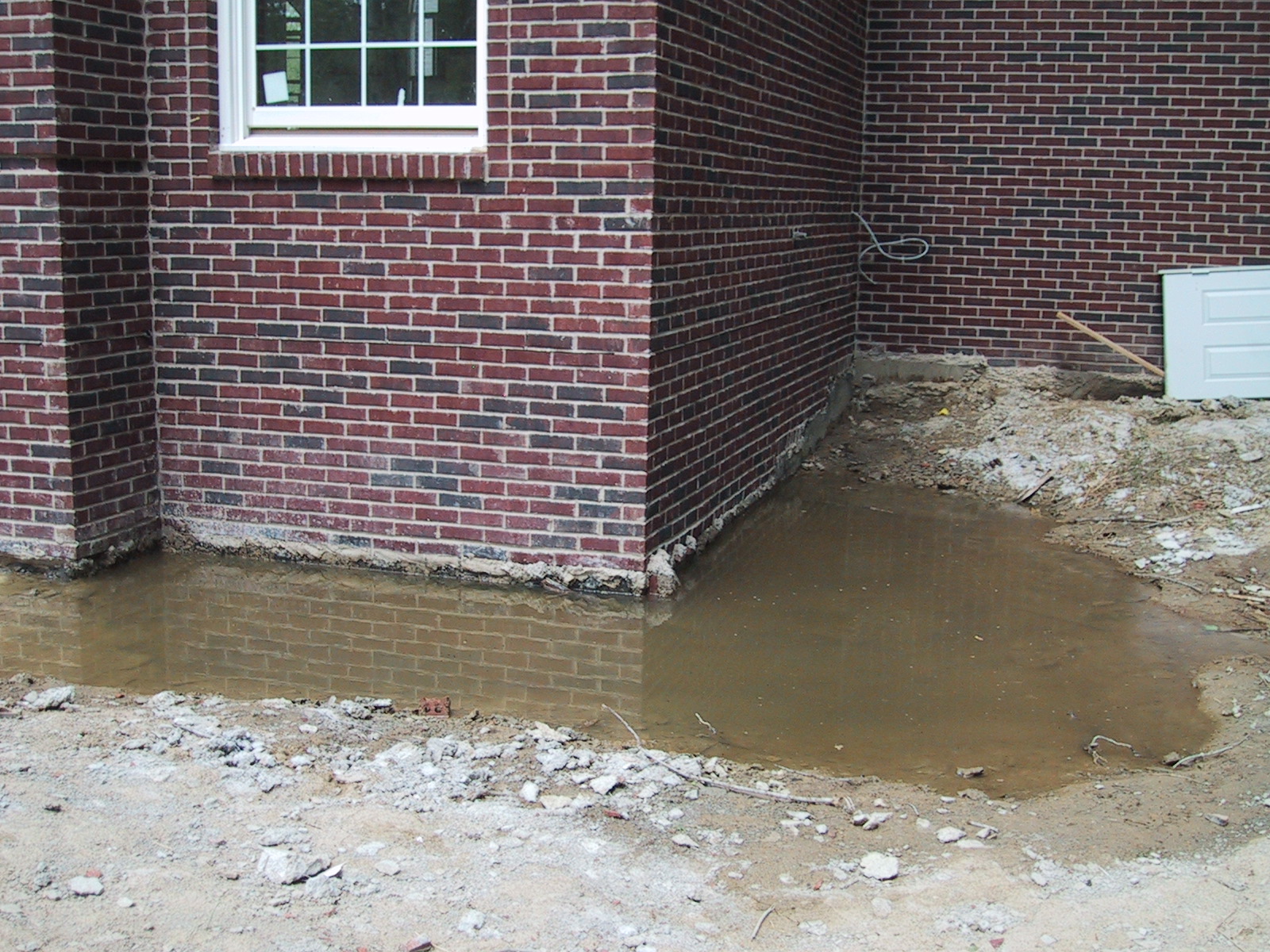 Water pooling at the foundation of a brick school building.