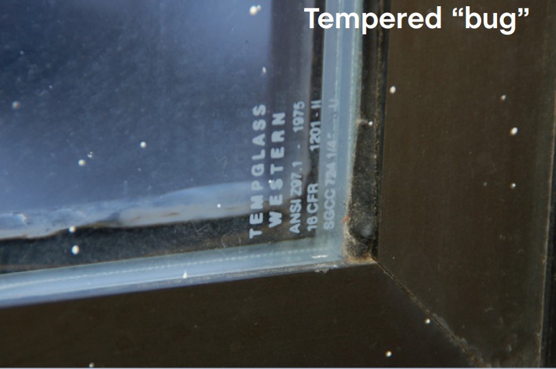 A tempered glass window can be identified by the “bug” or white etched  label at one corner of the window.