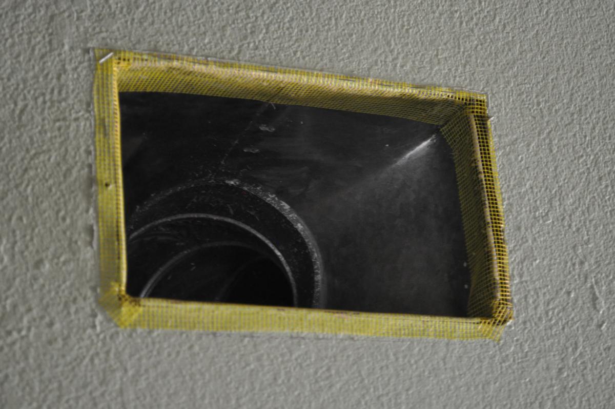 Fiberglass mesh tape is installed around a duct boot in preparation for air sealing with mastic.