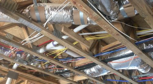 The ducts are located in conditioned space in open-web joists between the floors and supported to prevent sagging.