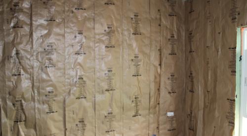 This fiberglass batt insulation has a kraft paper facing that is correctly stapled to the face rather than the sides of the wall studs to minimize compression.