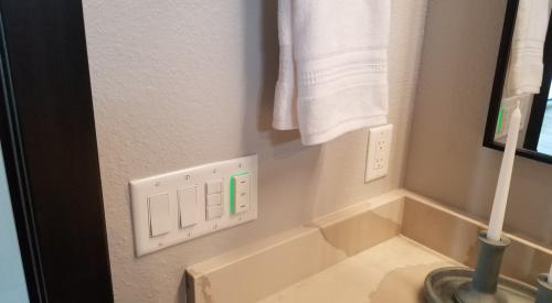 The green-lit panel next to the fan and light switches is an indoor air quality sensor that will automatically turn on the exhaust fan if it detects a rise in humidity or indoor air pollutants. 