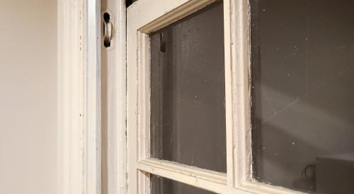 The pulleys in this old window frame were once used for counterbalancing weights to help raise and lower the window; this window can be restored with new pulley ropes or the weight pockets can be insulated with caulk and rigid insulation.