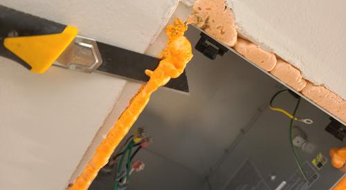After spray foam dries, a utility knife can be used to carefully trim excess foam around the exhaust fan housing