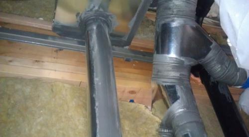 Sheet metal and mastic provide air sealing around a flue pipe. 