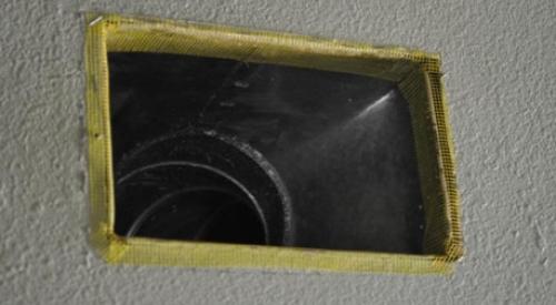 Fiberglass mesh tape is installed around a duct boot in preparation for air-sealing the seams with mastic.