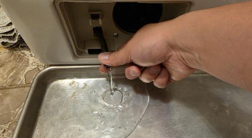An old baking pan makes a handy container to catch water when you disconnect the emergency drain hose to clean the drain pump filter.