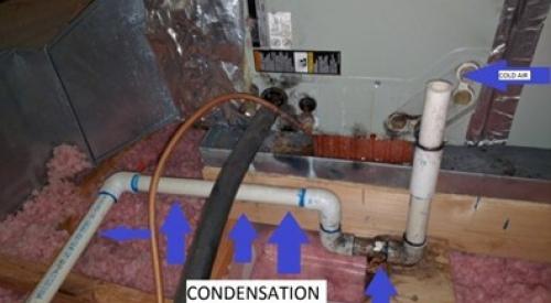 The uninsulated condensate line on this air conditioner located in an unconditioned attic is showing signs of condensation including wood staining at the elbow, discoloration at the joint, and liquid condensation on the pipe.