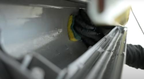 An HVAC contractor is deep cleaning the surfaces inside a minisplit heat pump that can only be reached when the blower wheel is removed