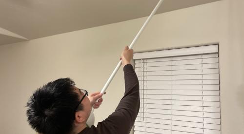 After completing the air leakage tests, the energy rater uses a broom handle to remove the register-sealing tape.