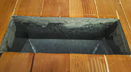 The seam between this duct register and the wood flooring is sealed with caulk to prevent air leakage into the house from the crawlspace below.