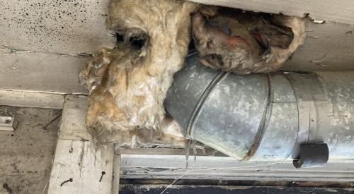 The fiberglass insulation stuffed into the large hole around this HVAC duct will not prevent air leakage from the unconditioned basement to the conditioned space above; the large gap should be sealed with a rigid air barrier and caulked or spray foamed. 