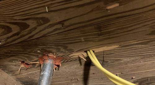 The electrical conduit (metal) on the left has been sealed to the subfloor using fire-rated caulk, while the penetration for the yellow electrical wire on the right has not been air-sealed yet.