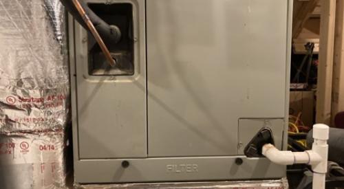 The filter access panel on this vertical upflow air handler is located between the return ductwork below and the coils above.