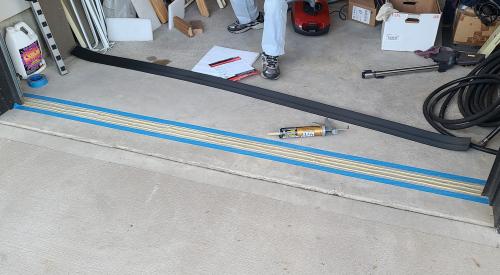 Garage door threshold weatherstripping is ready to be installed on the garage floor beneath the garage door.