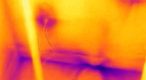 This IR camera image shows air leakage indicated by the dark purple streaks along the bottom plates and below the window sill, as well as some heat loss at the electric outlet. 