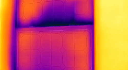 The dark purple patches at the sill and streaks at the meeting rail of the window in this IR camera image indicate heat loss and significant air leakage.