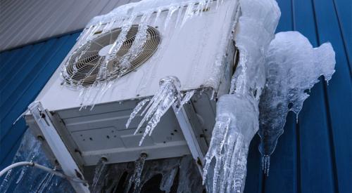 This heat pump compressor unit is elevated to avoid ground moisture and flooding, but water dripping from the roof above froze on the unit in winter, encasing it in ice.