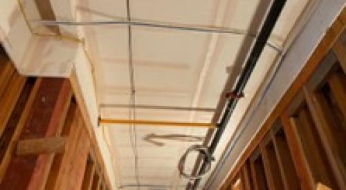 The ceiling and sides of this corridor service chase in a multifamily building are air-sealed with mudded and taped drywall prior to installing pipes, wiring, and ducts.