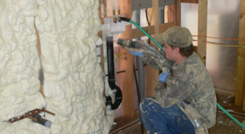 An installer fills these wall cavities with spray foam insulation, which will be trimmed flush with the stud faces after it dries and hardens.