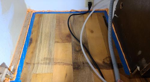 The wood flooring was taped off prior to installing the canned spray foam to protect the wood surface.