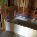 A rigid air barrier of non-paper-faced gypsum board is installed before the bathtub is installed and all seams are caulked