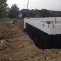 Concrete is poured into the rigid foam shell of the insulated concrete form (ICF) walls; a plastic water barrier has already been installed to protect the below-grade wall surfaces.