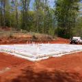 To help keep the monolithic slab-on-grade foundation dry, the site’s surfaces is graded away from the structure, the slab is poured on a bed of gravel, and using a vapor barrier will separate the foundation from the sill plates. 