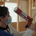 Right – A student uses a powered caulk gun to air seal wood-to-wood seams.