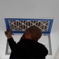 Right – An HVAC contractor installs a 4-inch-thick MERV 13 filter at the intake grille of this return air vent to prevent dust, allergens, smoke, and viruses from entering the duct system.