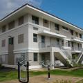A resilient multifamily building in Puerto Rico constructed of concrete on a raised slab foundation with a hip roof design for wind resistance and deep overhangs and permanent awnings to keep sun and rain off windows.