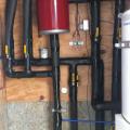 The home integrates roof-mounted solar hot water panels with an air-to-water heat pump; both sources feed into an 80-gallon stainless steel tank.