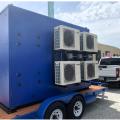 This packaged central heat pump water heating system has the heat pumps on the exterior of the blue enclosure, and the storage tanks, temperature maintenance equipment, mixing valve, and control modules on the inside