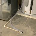 Condensate from this heat pump water heater is routed to a nearby floor drain, shared with the condensate lines from a condensing gas furnace and an air conditioning coil