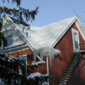 The icicles and the bare spot along the left roof ridge indicate that heat from the second-story room may be heating the underside of the roof deck, melting the snow and likely leading to ice dam formation.