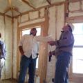 A builder, energy efficiency consultant, and crew supervisor inspect a spray foam installation. 