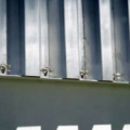 This metal shutter has top and bottom tracks that are permanently anchored to the wall (FEMA 577).