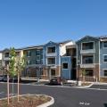 The roofs of the apartment buildings, community buildings, and carports are topped with solar panels in this affordable, zero energy multi-family housing complex.