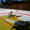 The builder laid down a 4-inch base of aggregate rock, then covered that with a plastic vapor barrier that is taped at all seams and around all penetrations before installing the rigid foam under-slab insulation.