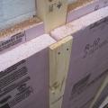 This close-up of an exterior wall retrofit of a masonry brick home shows the fluid-applied water and air control layer (white), 2x4 furring strips and two layers of rigid foam insulation (pink), then 1x4 furring which provides a ventilation gap