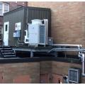 Central heat pump water heaters like this fully packaged system provide efficient, reliable domestic hot water for multifamily buildings; storage tanks are within the enclosure, and the heat pump is seen just outside.