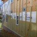 Holes in the exterior walls are flashed and flashing is integrated with housewrap before installing rigid mineral wool insulation.