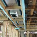 The main trunk line of the ducts runs within an insulated duct chase installed in a notch designed into the roof trusses that runs the length of the home to provide supply air directly to most of the home’s ceiling registers.